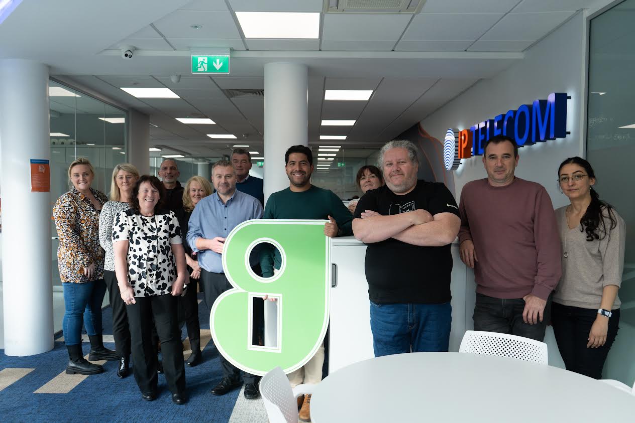 A group picture of IP Telecom members holding the Guaranteed Irish  'G' sign 